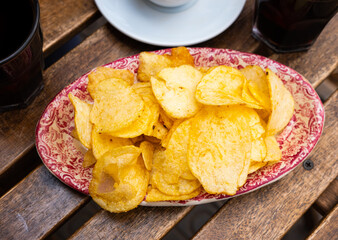 Service plate full of round potato chips and a glass of vermouth with orange slice