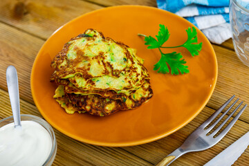 Top view of zucchini pancakes with white sauce at plate on table