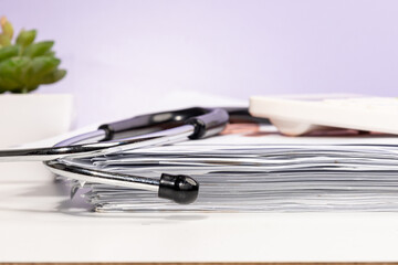 A neat stack of medical papers rests on a doctor’s desk, surrounded by essential medical tools...