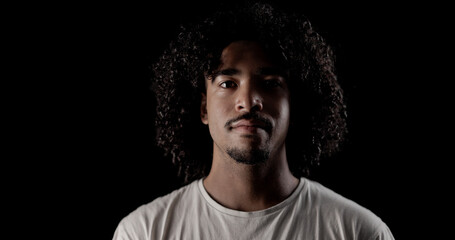 Studio portrait of confident young african american man with curly hair posing on black background