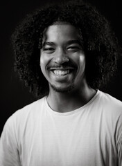 Portrait of a cheerful young african american man with curly hair, wearing a white t shirt, smiling...