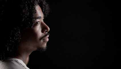 Profile of a serious young african american man looking away on a black background