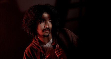 Portrait of a young African American man illuminated by a red light in a dark room