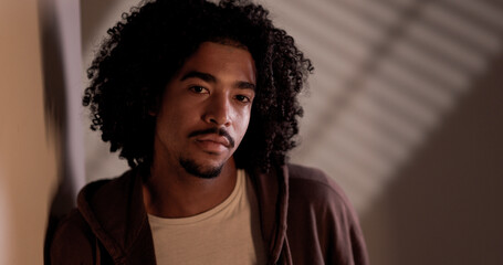 Portrait of a serious young african american man with curly hair and goatee, wearing a casual white...