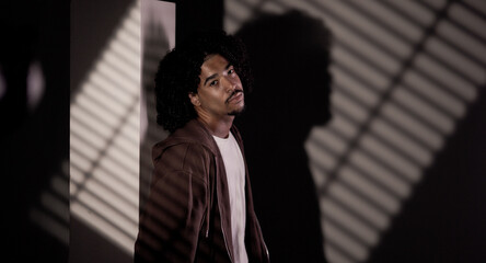 Portrait of a young african american man with curly hair, wearing a brown hoodie and a white t...
