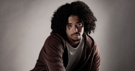 Portrait of a serious young african american man with curly hair and goatee wearing casual clothes,...
