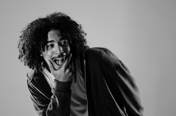 Black and white portrait of a young man making a funny face, sticking out his tongue and holding...