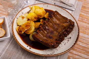 Grilled pork ribs rack with barbecue sauce garnished with potatoes