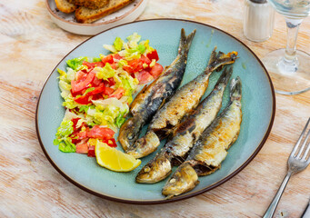 Appetizing fried sardines with a light vegetable salad made from lettuce, tomatoes and red pepper....