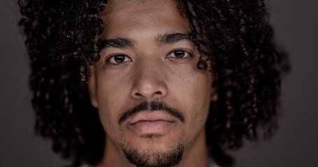 Close up portrait of a serious young African American man with curly hair and goatee, conveying...