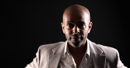 Portrait of a serious African American businessman posing in a studio, wearing a light gray suit...