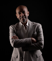 Portrait of a confident african american businessman smiling with crossed arms on black background