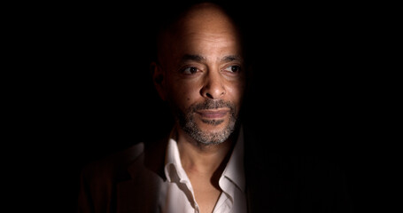 Portrait of an african american businessman illuminated by a strip of light in a dark environment