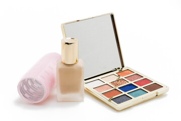 Cosmetics and Hairstyling Set with Eyeshadow Palette, Foundation, and Pink Self-Adhesive Hair Roller Isolated on White Background