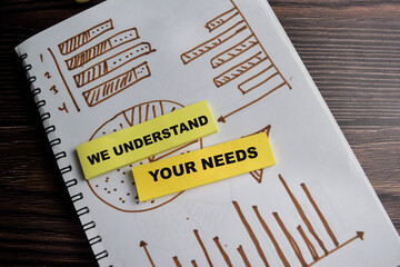 Concept of we understand your needs write on sticky notes isolated on Wooden Table. Business analysis chart