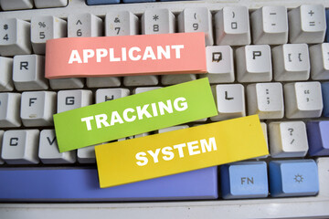 Concept of Applicant, tracking, and system write on sticky notes isolated on keyboard.