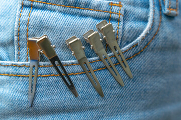 Close-up of silver metal hair clips attached to a blue denim pocket, representing fashion and style...