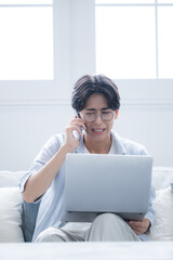 スマホで通話しながら謝罪する、パソコンを見る眼鏡をかけた男性