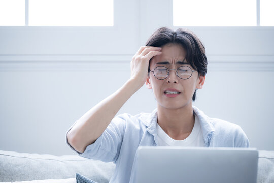 Man holding his head while looking at a computer A look of annoyance and distress A man holding his head after making a mistake or failure at work