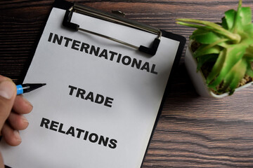 Concept of International trade relations write on clipboard isolated on Wooden Table.