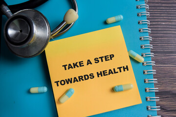 Concept of take a step towards health write on sticky notes isolated on Wooden Table. healthcare...