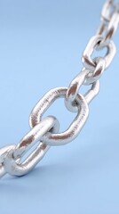Obraz premium Close up of a metallic silver chain with interlocking links against a solid blue background