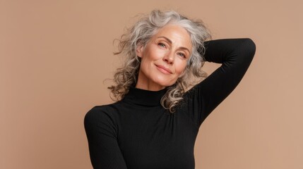 Elegant middle-aged woman with curly hair posing against a warm, neutral background and smiling softly during a portrait session