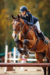 Rider jumps over obstacles during equestrian competition in a lush outdoor arena near golden autumn trees