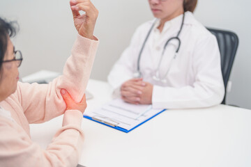 Elderly Woman having elbow ache and consulting doctor in hospital. muscle pain due to lateral...