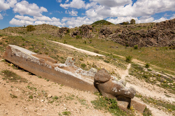Photo of Fasillar monument with view of cloudy sky and mountains.