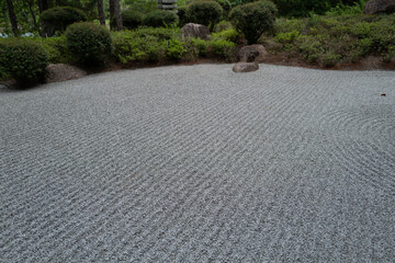 Close-up of a meticulously raked gravel surface in a Zen garden, showing textured parallel lines...