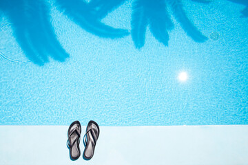 Pair of slippers on the edge of the swimming pool from above