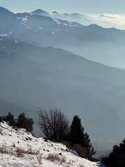 Serene winter landscape view from a snowy peak. Layers of mountains disappearing into the morning...