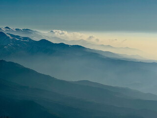 Hazy blue mountain layers fading into the distance. Scenic landscape with snow-capped peaks and...