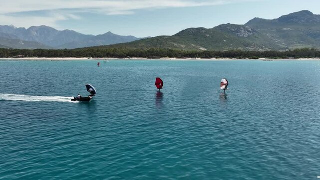 Wing Foilers and Speedboat in Motion Across Clear Corsican Waters
