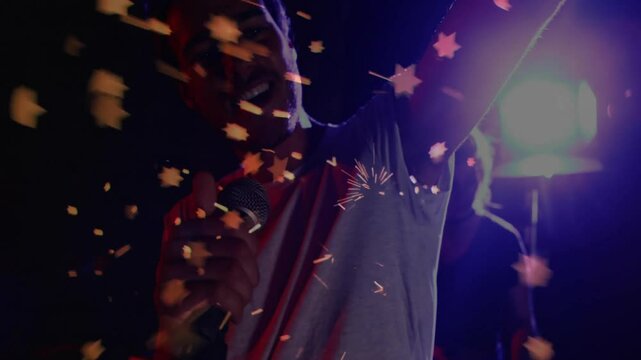 Lead singer grabbing mic causing confetti swirling and spotlight lighting bandmate musician behind