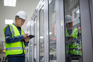 Engineer wearing safety helmet and reflective vest performs substation inspection to ensure...