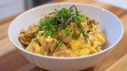Delicious Oyakodon with Tender Chicken, Egg, Rice, and Green Onion Garnish in a Bowl