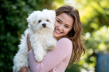 A woman holding a small white dog in her arms.