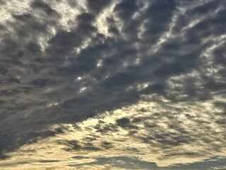 Dramatic sunset sky with layered clouds and soft golden light breaking through. A natural cloudscape background with a moody and atmospheric feel, perfect for creative or editorial use.