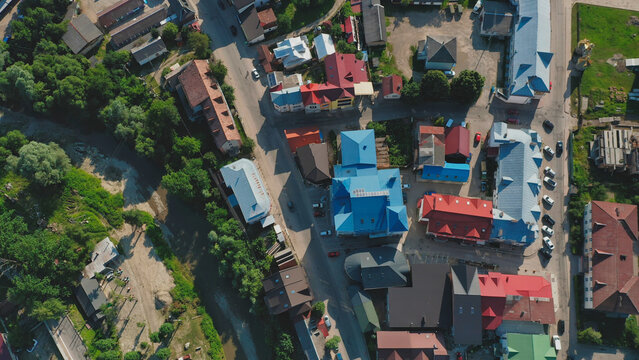 View of a township from above showcasing colorful rooftops and winding roads surrounded by greenery