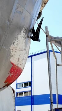 During the daytime, we see a large vessel in dry dock at the Shipyard for inspection and repair of the hull and propeller. Scaffolding surrounds the vessel.
