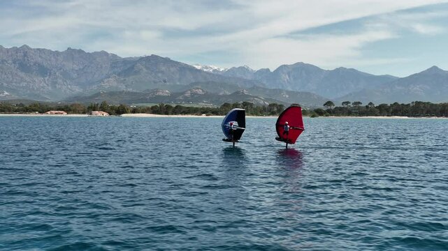Two Wingfoil Racers Gliding Along Scenic Coastline