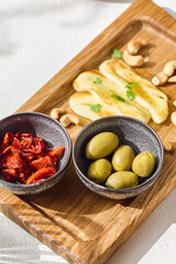 Grilled halloumi with green olives and sun‑dried tomatoes, bright lighting, overhead wooden board composition