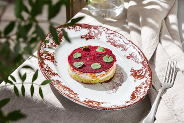 Herring under fur coat salad in bright rustic lighting, overhead composition on vintage plate