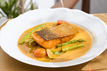 Salmon steak with asparagus and bisque sauce, bright natural light, overhead composition
