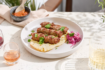 Kebabs with pita bread under bright natural lighting, overhead minimalist composition