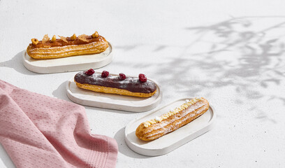 Eclairs assortment on bright minimalist tabletop, overhead flatlay with empty copyspace