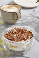 Tiramisu with coffee in bright natural light, closeup composition on a minimal table