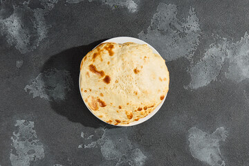 Tandoor flatbread on white plate, bright lighting, overhead minimalist composition